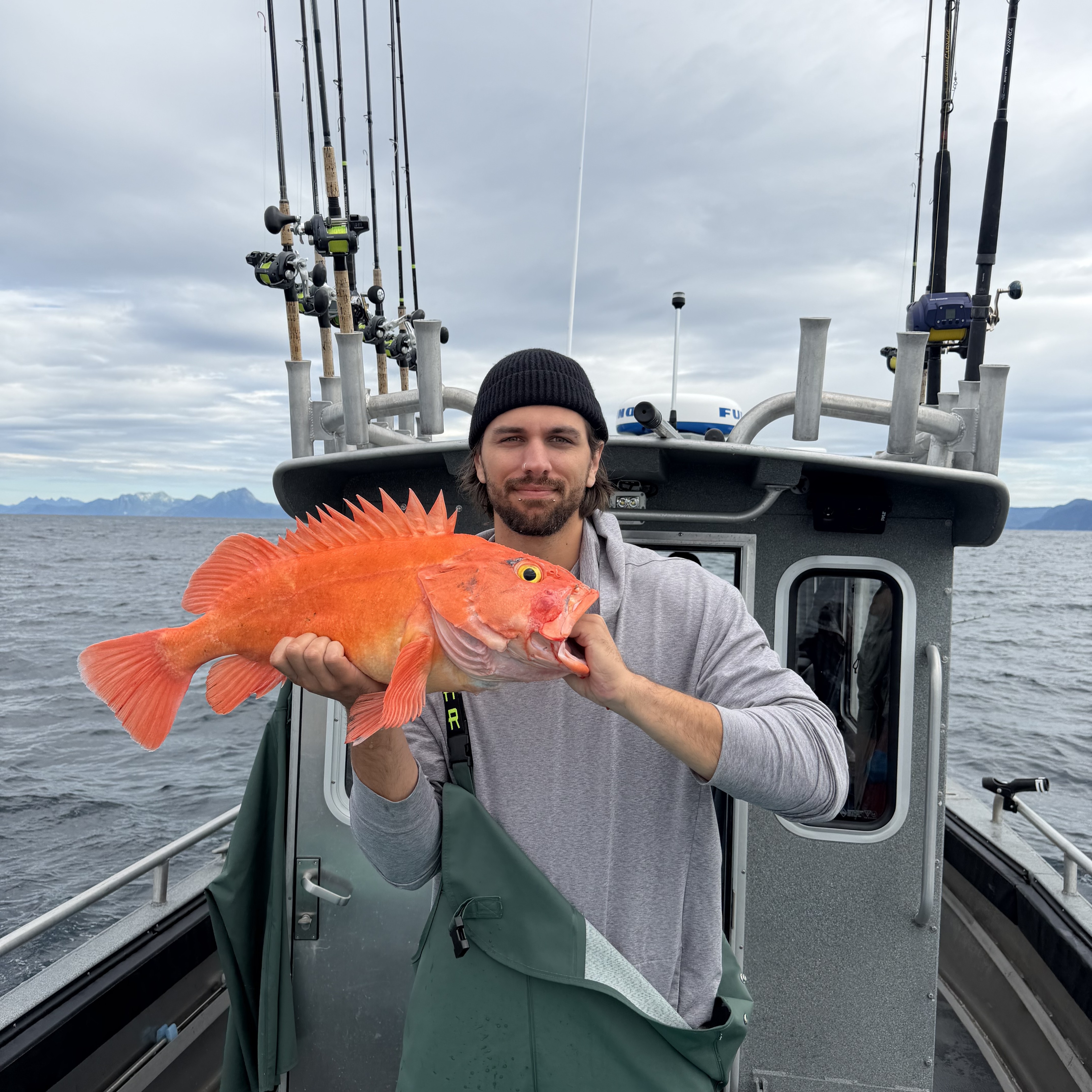 Axa holding a bright orange rockfish on a fishing boat