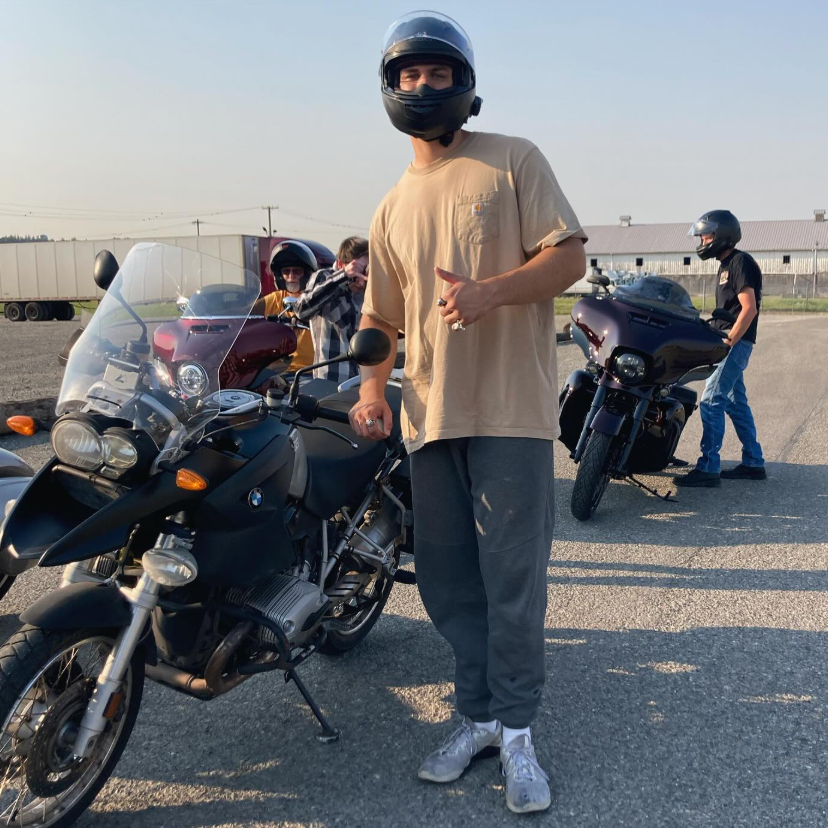 Axa in a helmet standing beside his BMW motorcycle
